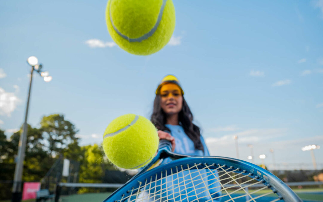 Tennisspielerin jongliert Bälle mit ihrem Schläger: Mit den richtigen Aktien lässt sich auch in Sport investieren.