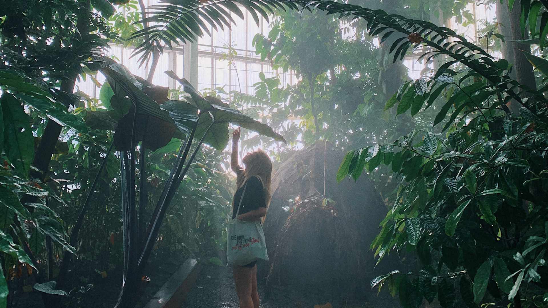Junge Frau bewundert die tropischen Pflanzen im botanischen Garten bei ihrem günstigen Winter-Date.